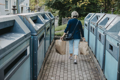 Rear view of woman carrying paper bags with recycling