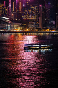 Illuminated modern buildings by river at night