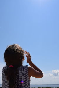 Rear view of girl against blue sky