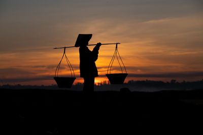 Silhouette man standing against orange sky