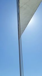 Low angle view of bridge against buildings against clear blue sky