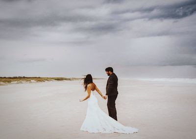 Rear view of couple standing on land against sky