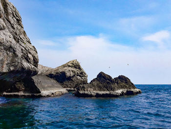 Scenic view of rocks in sea against sky