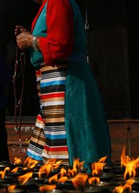 Close-up of fire against woman with religious beads