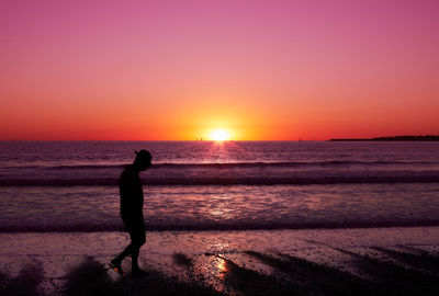 Silhouette woman standing on beach against sky during sunset