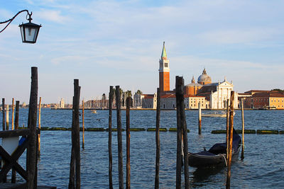 Wooden posts in sea against buildings