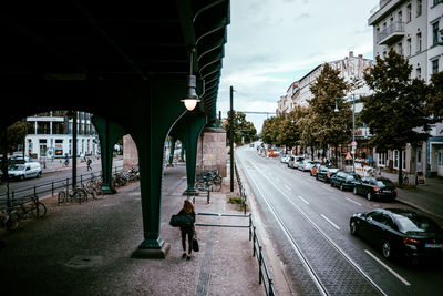 High angle view of woman walking on sidewalk by bridge in city