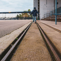 Rear view of man walking on railing