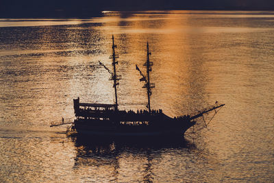 Silhouette man in boat on lake during sunset