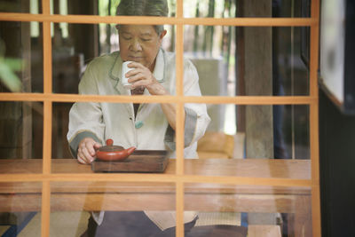 Portrait of young woman looking through window