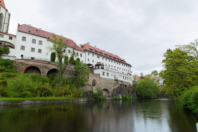 Arch bridge over river by buildings against sky