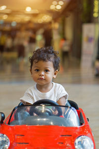 Close-up portrait of cute boy riding toy car