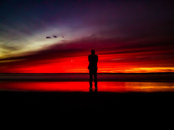 Silhouette man standing against dramatic sky during sunset