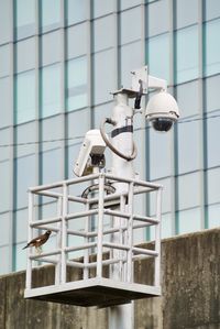 Low angle view of electric lamp against building