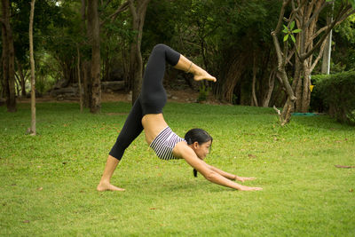 Woman practicing yoga on grassy field at public park