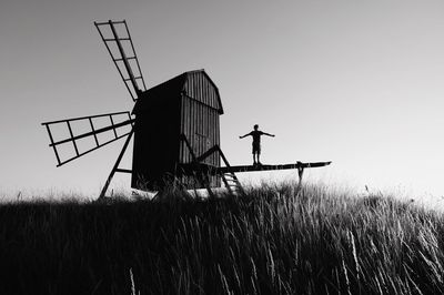 Silhouette traditional windmill on field against clear sky
