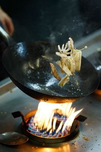 Close-up of hand holding wok pan with sea food inside