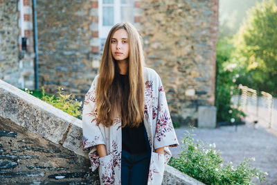 Beautiful young woman standing against wall