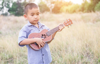 Boy playing guitar on field