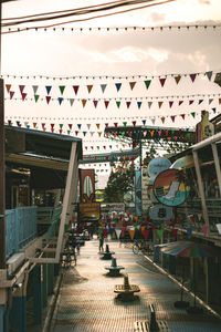 People hanging on staircase in city against sky