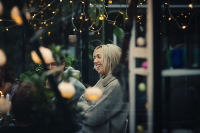 Rear view of woman standing by plants at night