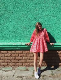 Full length of happy girl standing against wall