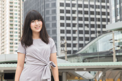 Young businesswoman standing against buildings in city