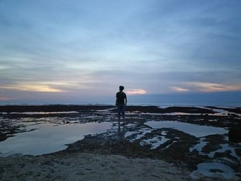 Man standing on beach against sky during sunset