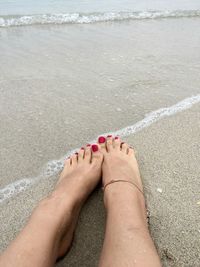 Low section of woman on shore at beach