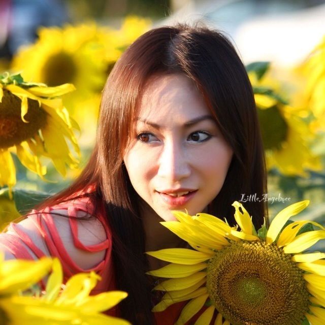 flower, person, yellow, focus on foreground, long hair, fragility, lifestyles, young women, headshot, childhood, leisure activity, girls, freshness, looking at camera, elementary age, smiling, close-up