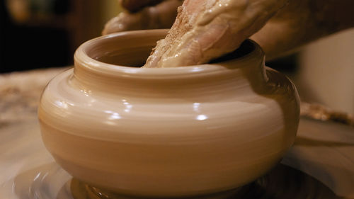 Cropped hand shaping clay pot