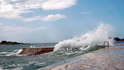 Waves splashing on sea against sky