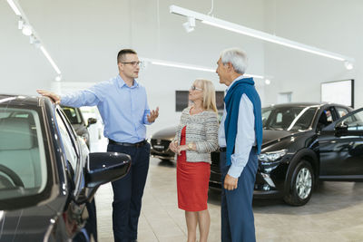 Senior couple couple talking with salesperson in car dealership