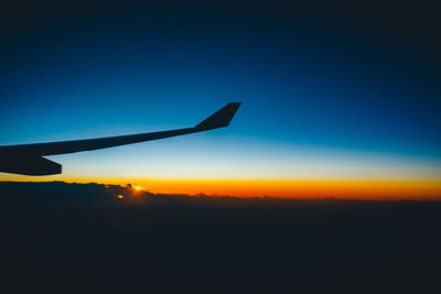 Silhouette airplane against clear sky during sunset