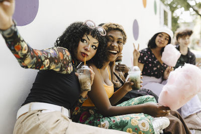 Happy teenage girl taking selfie with friends