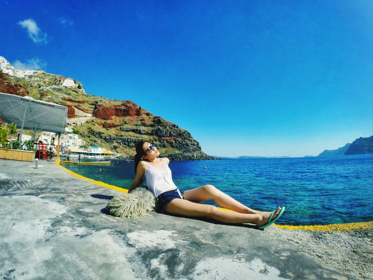 water, lifestyles, sea, leisure activity, young adult, blue, full length, sitting, casual clothing, beach, vacations, person, relaxation, clear sky, young women, shore, sky, nature