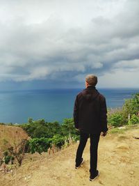 Rear view of man looking at sea against sky