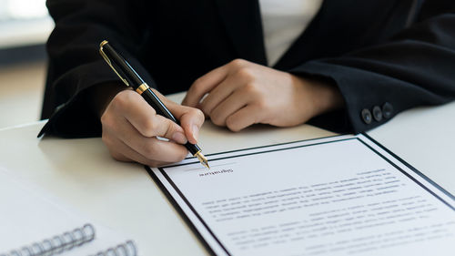 Midsection of man reading book on paper