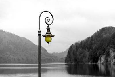 Street light by lake against mountains