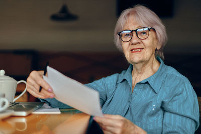 Senior businesswoman with document sitting at cafe