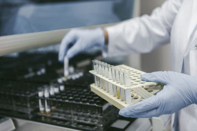 Midsection of scientist holding test tube rack at laboratory