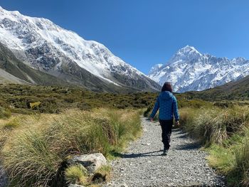 Rear view of man walking on mountain against sky