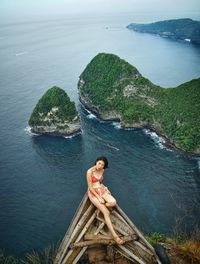 Young woman sitting on rock by sea