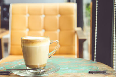 Close-up of cappuccino on table against chair