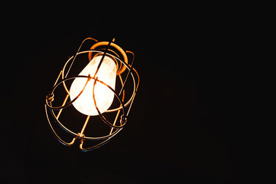 Low angle view of illuminated lamp against black background