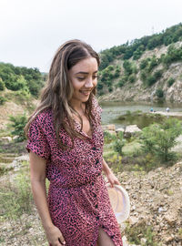 Beautiful young woman smiling while standing against water