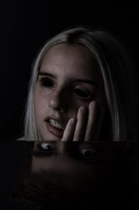 Portrait of young woman against black background