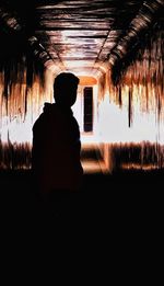 Rear view of silhouette man standing in tunnel