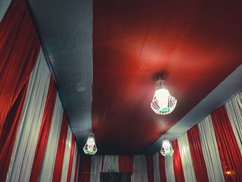 Low angle view of illuminated pendant lights hanging on ceiling of building