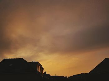 High section of silhouette buildings against dramatic sky